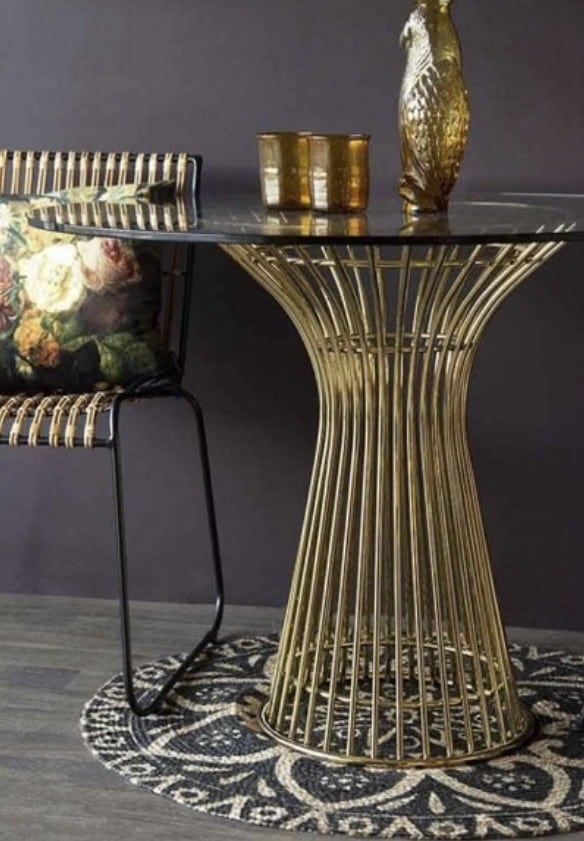 glass top Round dining table with sculptural brass pedestal base in a glamorous dining setting