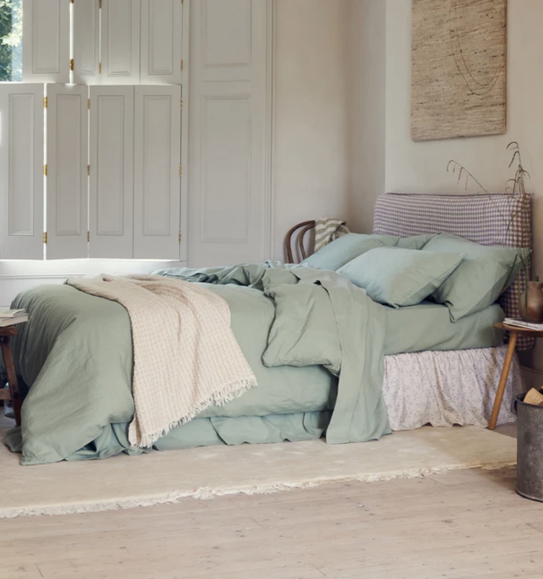 Green and beige bedroom with a poop of purple in the valance and the headboard