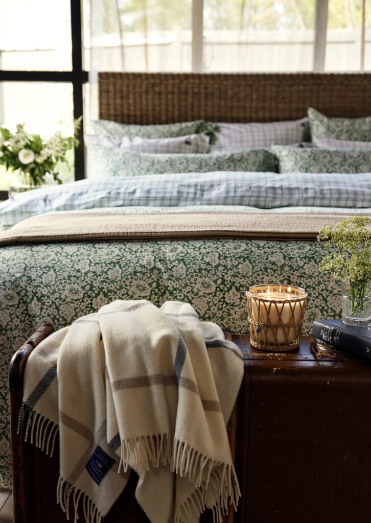 Green and beige bedroom with floral and gingham bedding, a rattan headboard, and soft natural light.