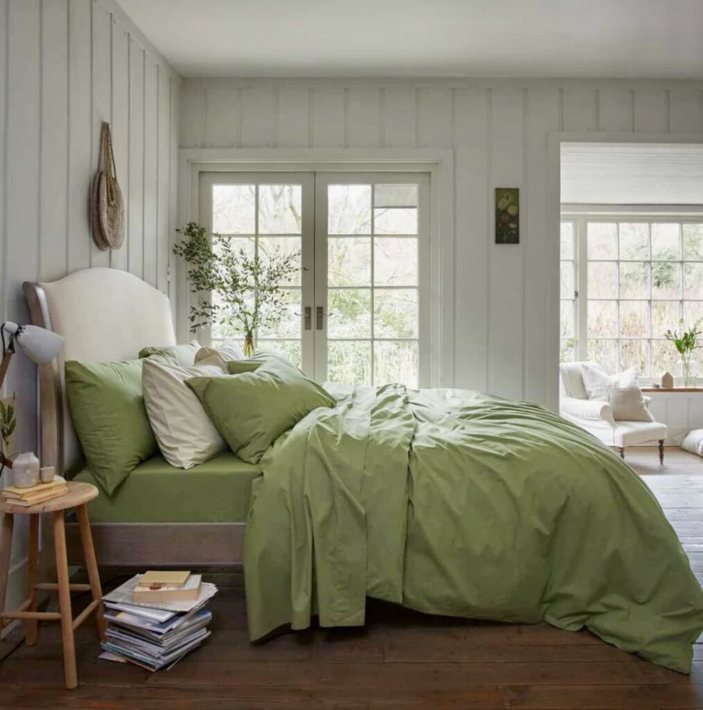 Light and airy green and beige bedroom featuring a pear-green duvet cover, white upholstered headboard, and minimalist decor with natural wood accents.