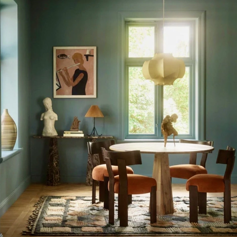 Oak pedestal round dining table styled with rust velvet dining chairs in a teal dining room