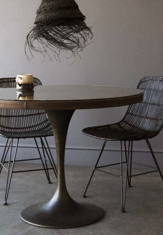 leather Round dining table with glass top and bronze pedestal base styled with modern wire dining chairs