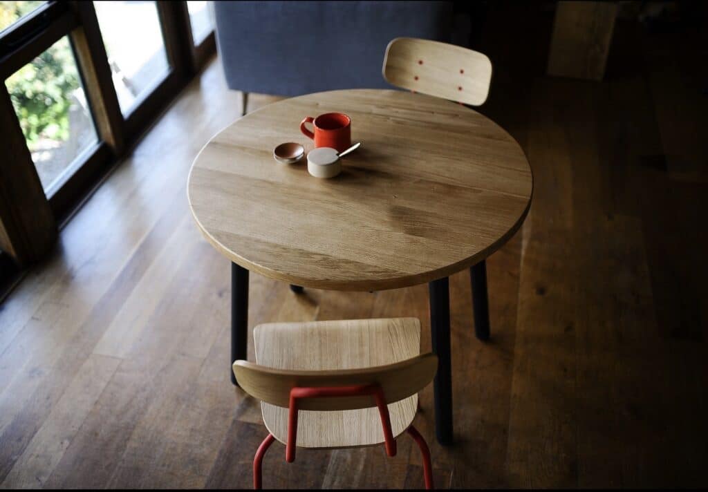 Affordable extendable solid oak dining table shown closed in a round shape with black legs in a compact dining space