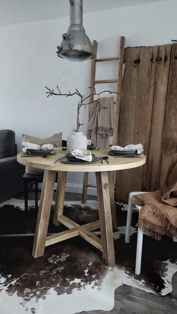 Small rustic round dining table with farmhouse wooden base styled in a cosy dining nook