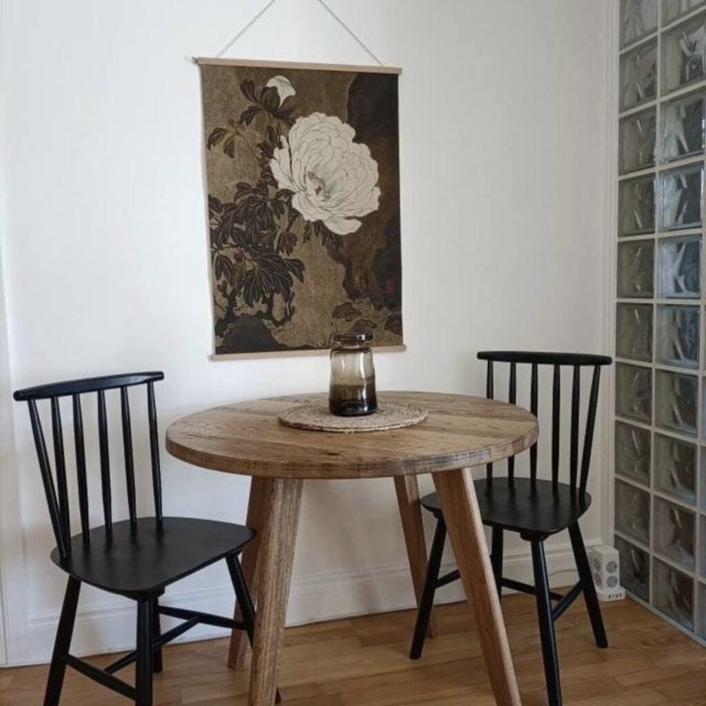 Small oak round dining table with angled wooden legs styled with black spindle chairs