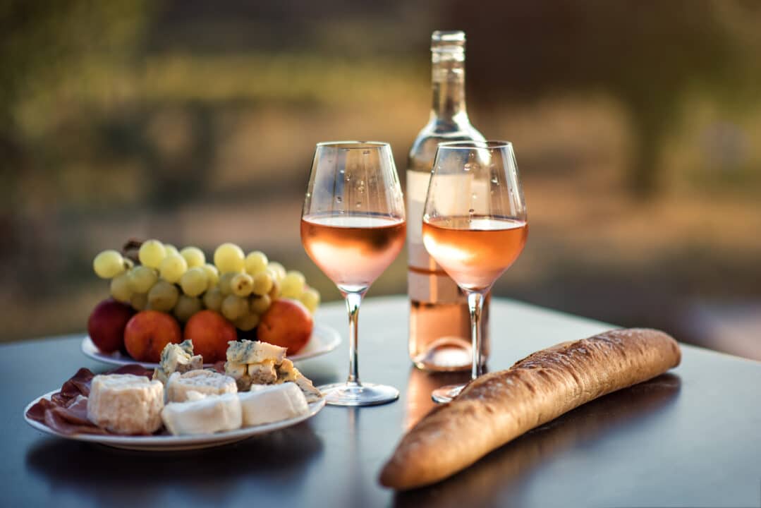 Glasses of Provence rosé wine in soft sunlight with cheese and bread