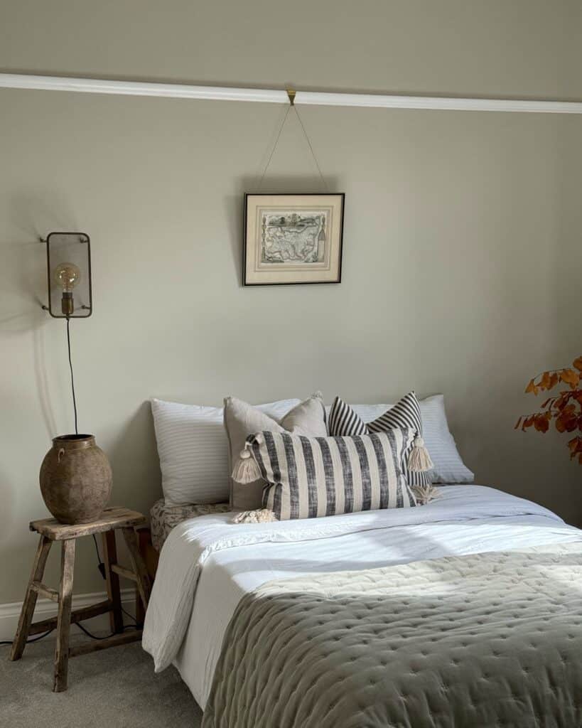 Beige small bedroom with Farrow & Ball Shaded White walls, striped cushions and rustic wooden stool bedside table