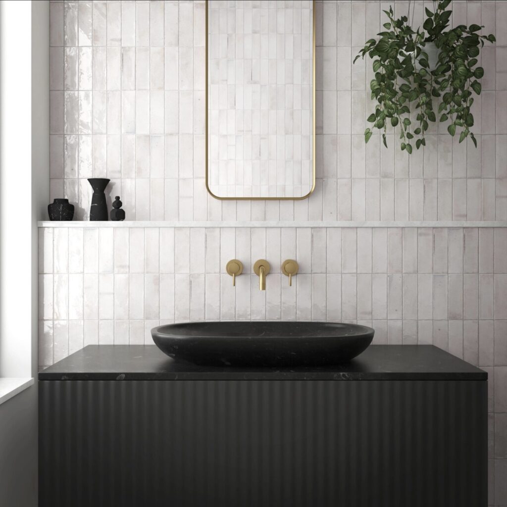 Black and white bathroom with Beijing white gloss Moroccan wall tiles, black basin, ribbed vanity, and gold fittings