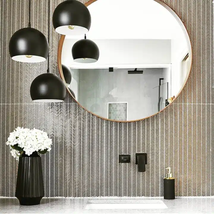 Black and white bathroom with herringbone Gravity Aluminium Arrow metal wall and round wood-framed mirror