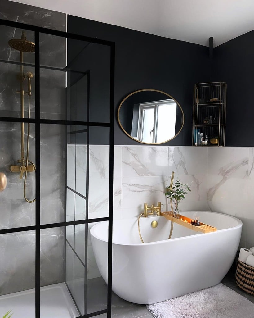 Black and white very small bathroom with crittall-style shower screen, marble tiles, freestanding bath and brass fittings