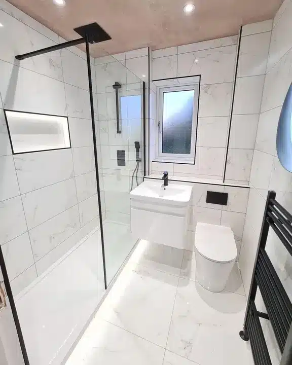 Small black and white bathroom shower room with Marmol Carrara Blanco tile and black towel rail