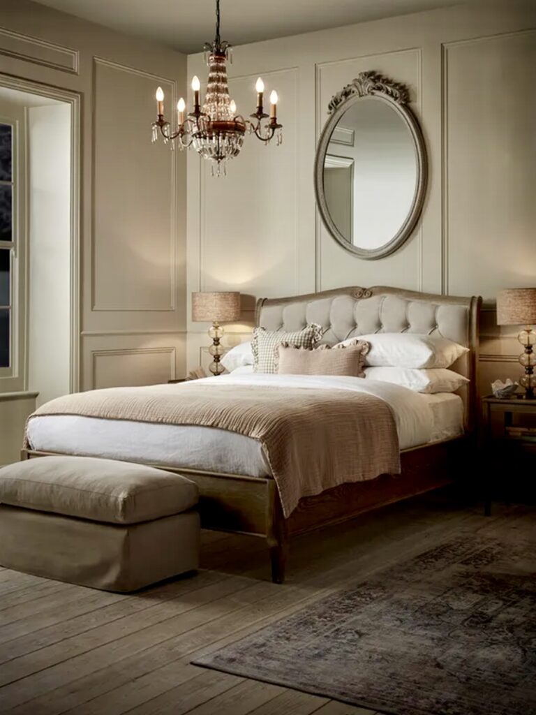 Elegant beige bedroom featuring a tufted kingsize bed, crystal chandelier, and panelled walls—showcasing classic beige bedroom ideas with timeless sophistication.