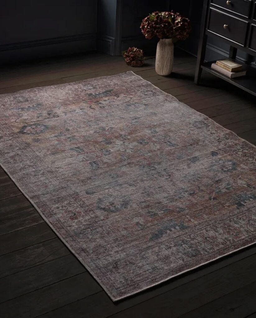 Vintage-style Nima rug with russet tones and a faded finish, complementing beige bedroom decor with warmth and traditional charm.