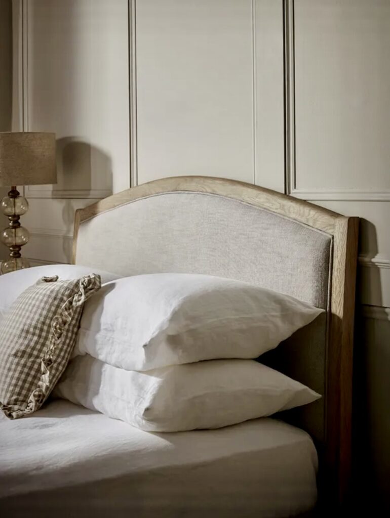 Close-up of the Myla Bed with natural wood frame and upholstered beige headboard, styled within a soft neutral beige bedroom décor scheme.