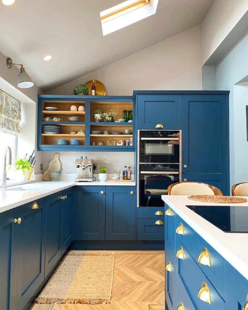 Hague Blue kitchen with floor-to-ceiling cabinets, gold cup handles, integrated open shelving, herringbone oak flooring and a skylight.