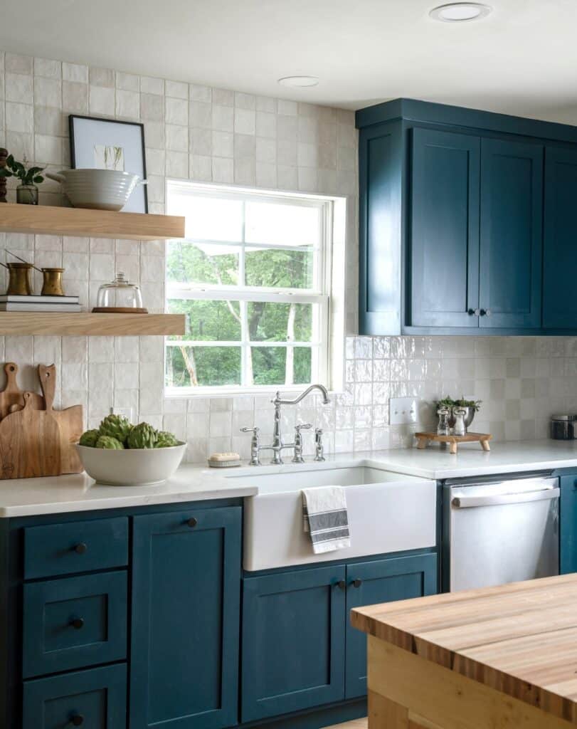 Hague Blue lower kitchen cabinets with white Belfast sink, zellige tile backsplash, natural oak open shelving and butcher block island.
