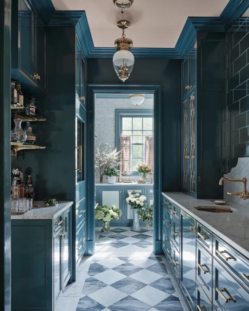 Inchyra Blue high-gloss butler’s pantry with floor-to-ceiling cabinetry, brass bar handles, marble checkerboard floor, globe pendant light and marble worktop.​​​​​​​​​​​​​​​​