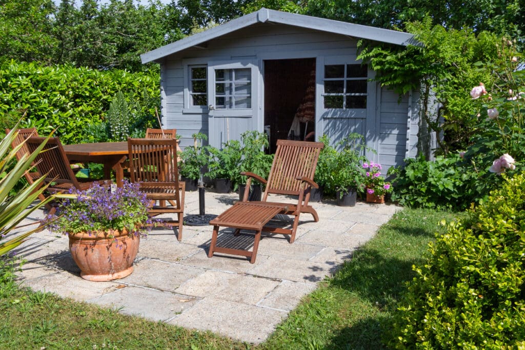 Painted blue grey garden summerhouse with terrace and garden furniture