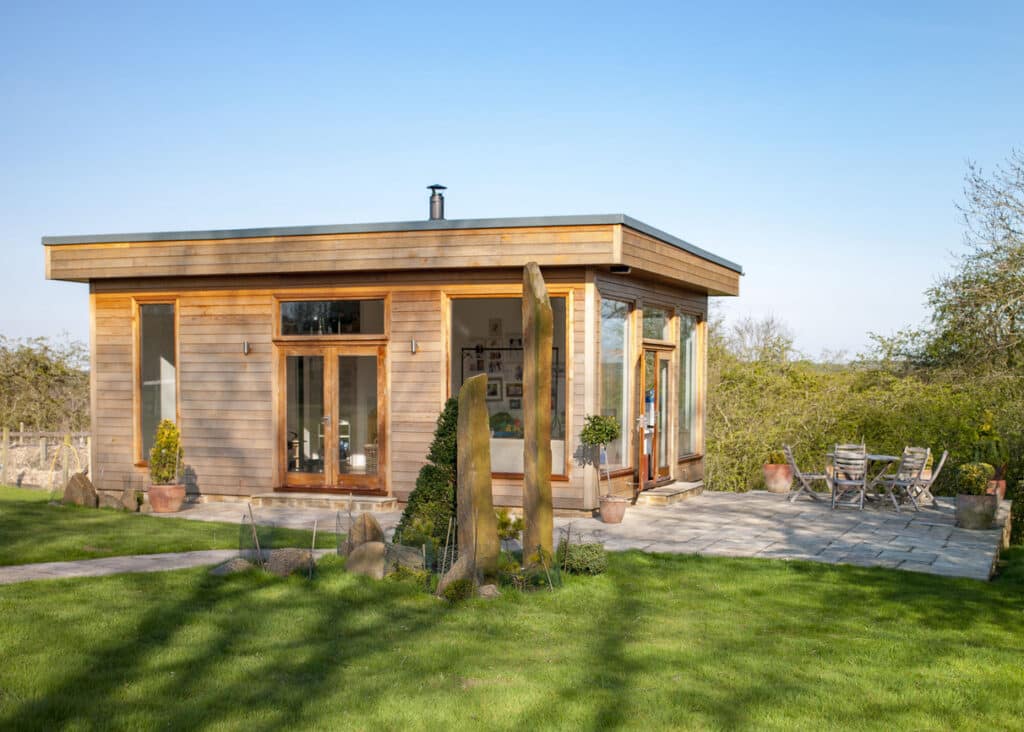 Modern cedar clad summerhouse with full-height glazing in garden