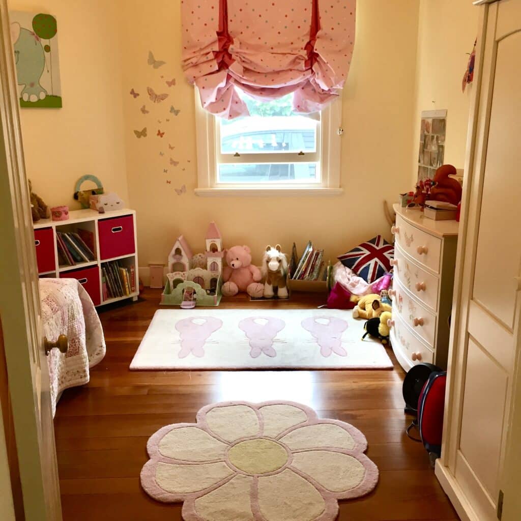 Little girls bedroom with yellow walls, flower rug, butterfly wall stickers and polka dot roman blind — little girls bedroom ideas