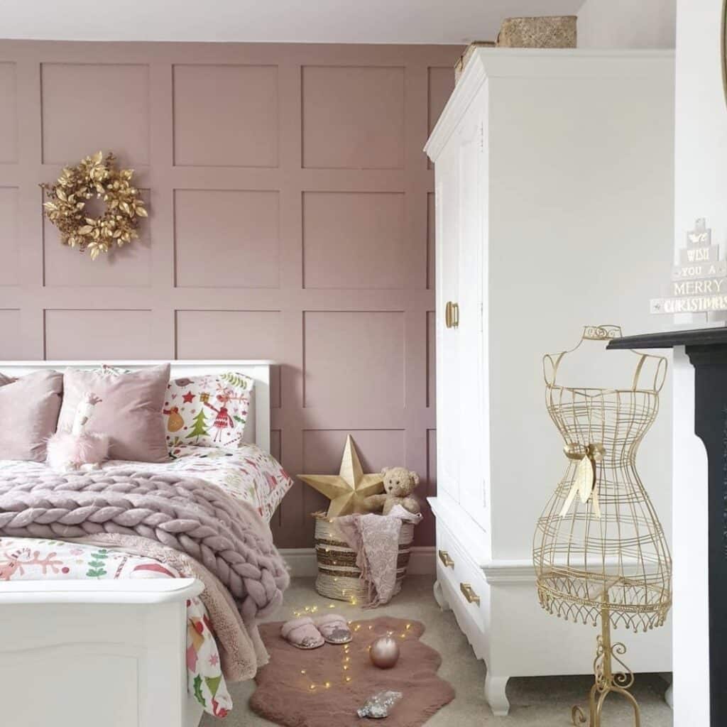 Girls bedroom with Farrow and Ball Sulking Room Pink panelled wall, white wardrobe and gold accessories