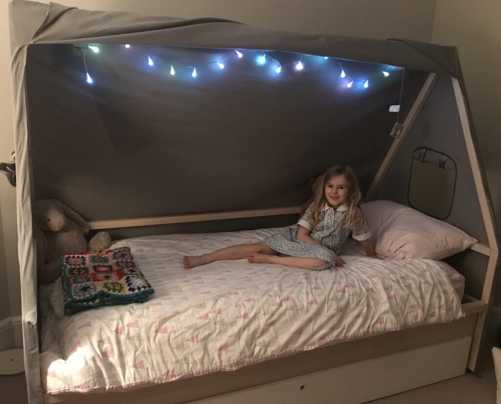 A girl’s house bed with grey canvas canopy and fairy lights — girls bedroom ideas