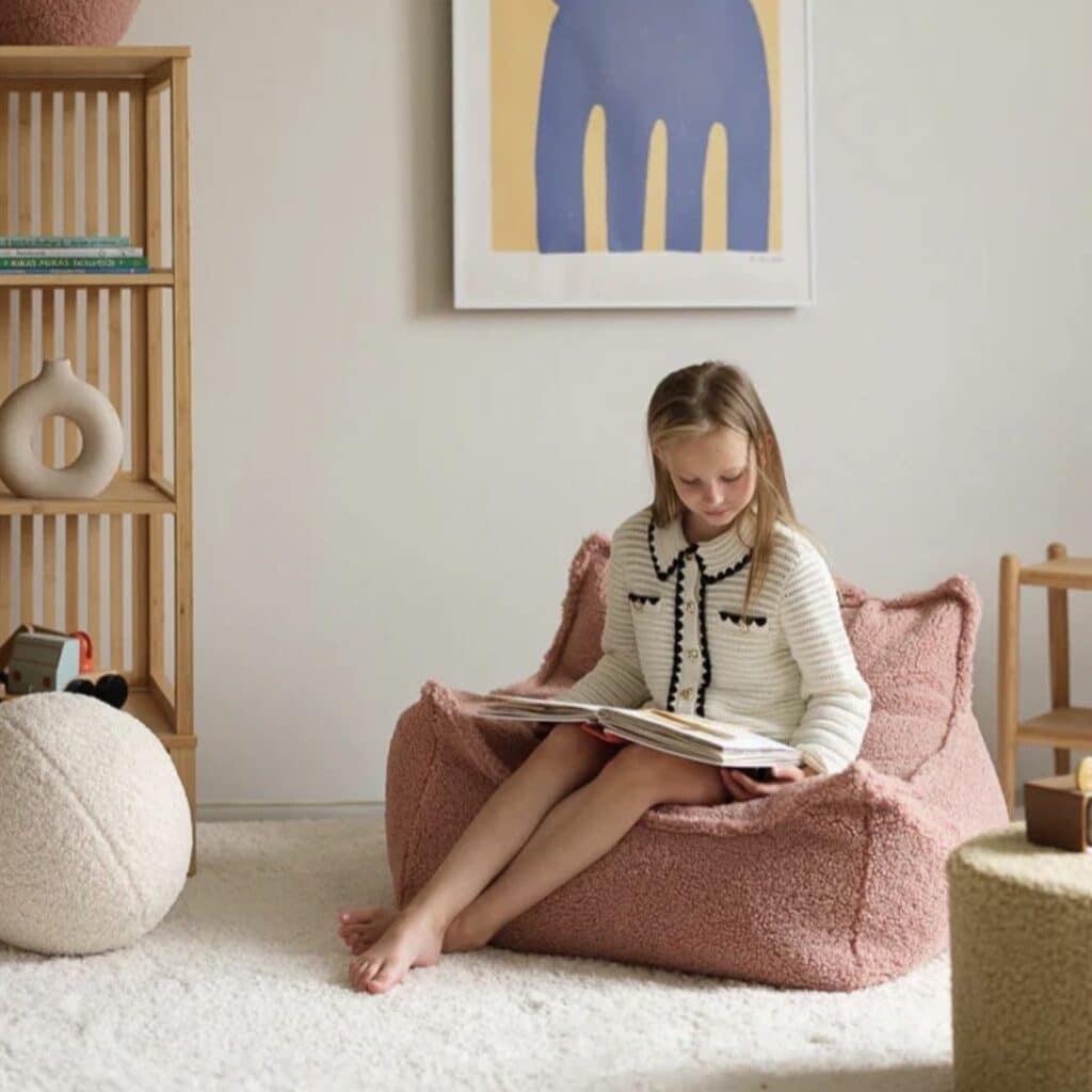 Girl reading in Wigiwama Beanbag Chair in Guava pink bouclé — girls bedroom reading corner ideas