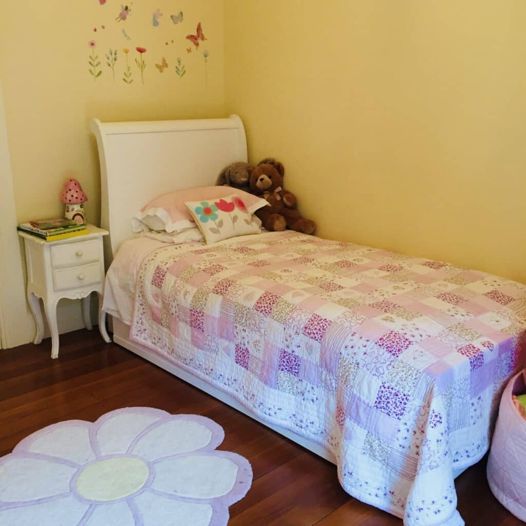 Little girls bedroom with yellow walls, patchwork quilt and flower rug — little girls bedroom ideas