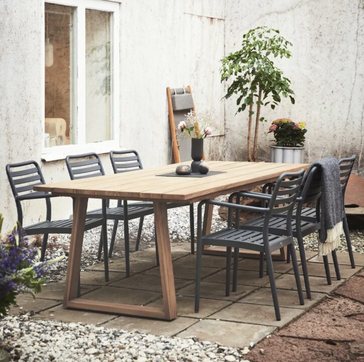 Stylish courtyard garden dining setup featuring a wooden outdoor table with metal chairs. A perfect inspiration for small courtyard garden ideas, combining modern design with natural elements.