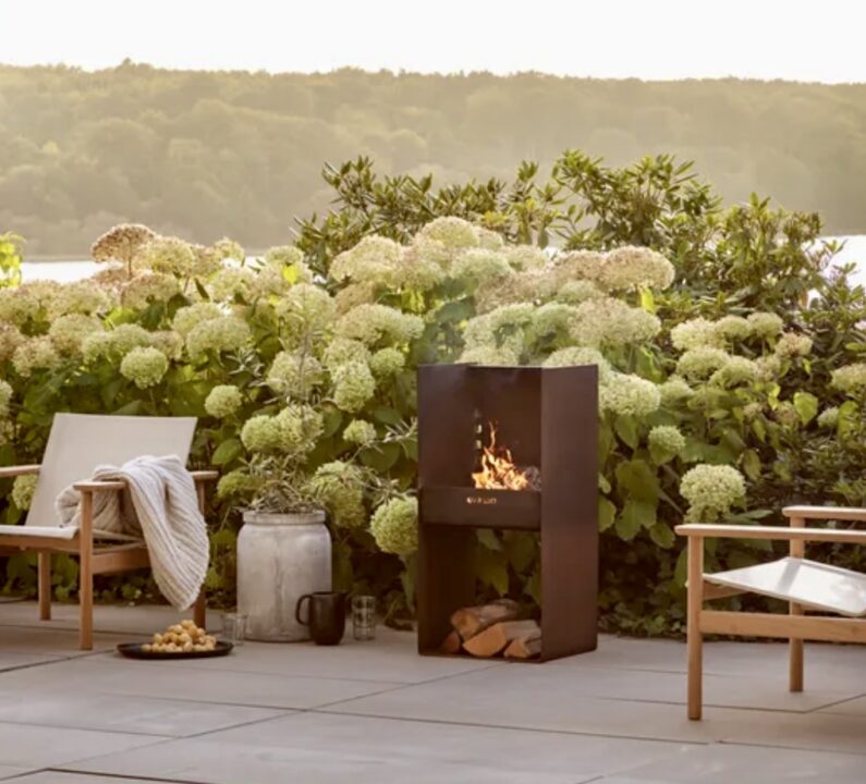 Modern firepit and grill in a beautifully paved courtyard garden, surrounded by lush greenery. A stylish and functional addition to small courtyard garden ideas, perfect for outdoor entertaining.