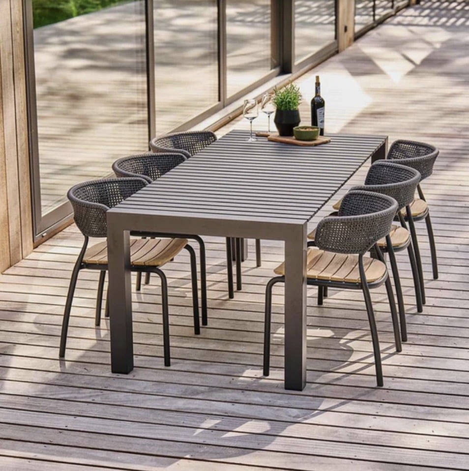 Mindo 111 extendable metal outdoor dining table (1.6m–1.9m x 0.9m) styled with six chairs on a timber deck, modern outdoor dining table idea.
