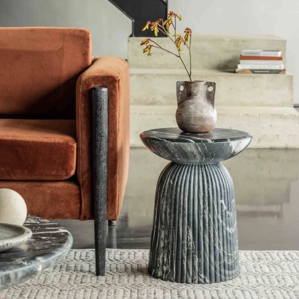 Mason stool side table by Atkin & Thyme with dark marble top and fluted stone base — unique stone side tables for living rooms.