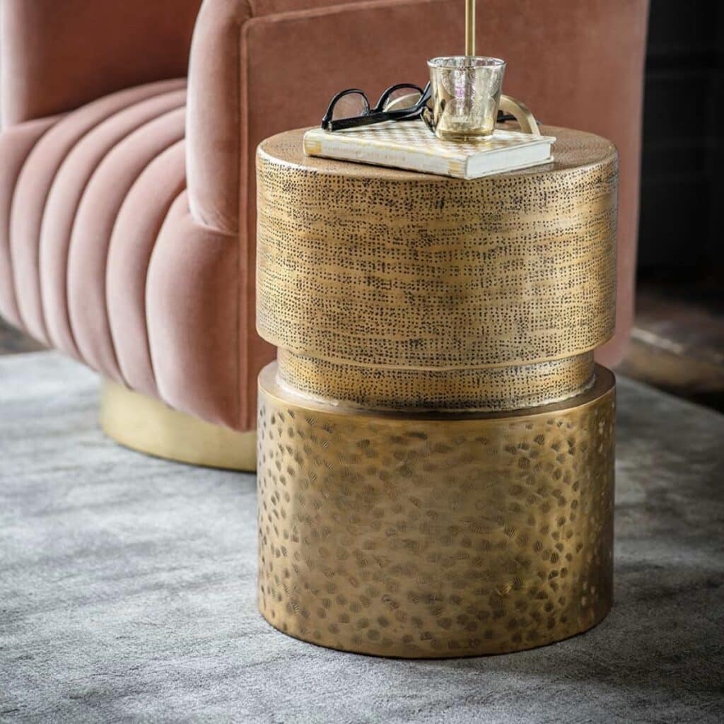 Unique side tables: Balzac side table by Atkin & Thyme with a hammered antique-gold metal finish beside a blush velvet sofa.