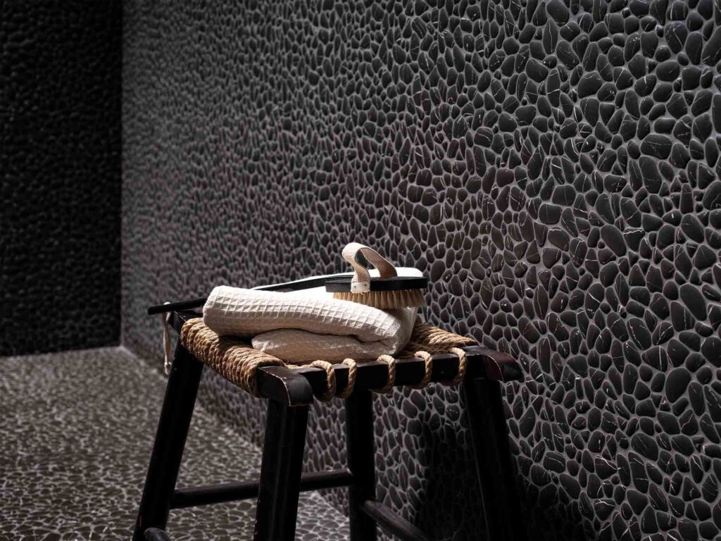 Black bathroom wall with pebbled Marquina marble tile texture