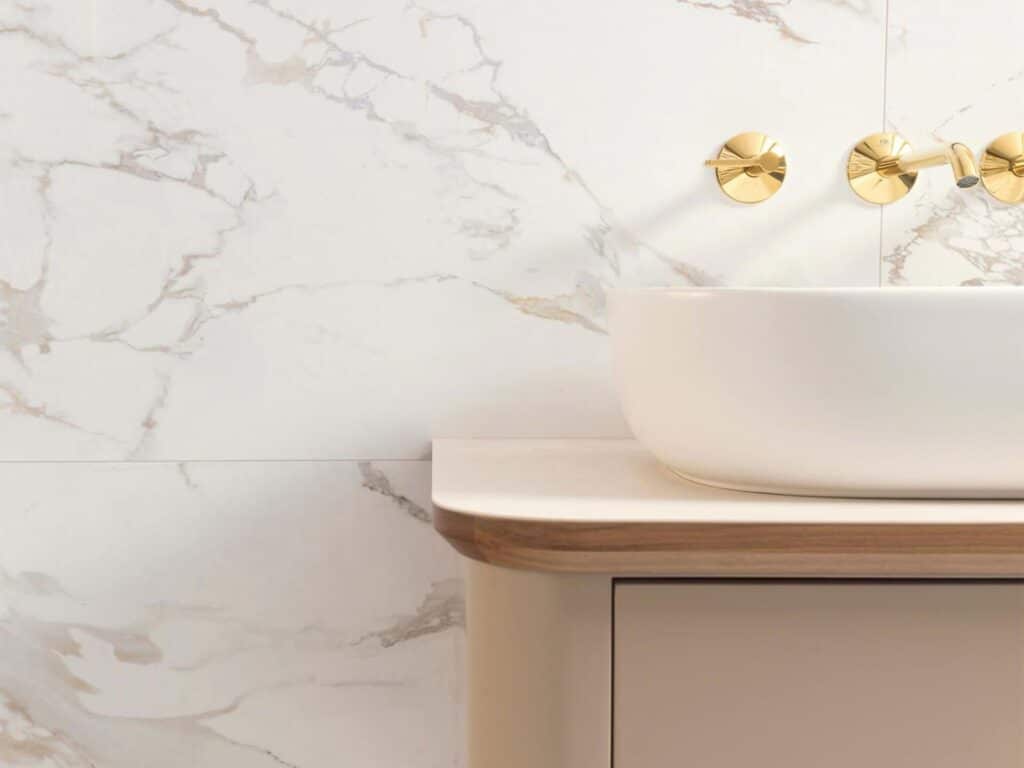 Massa 59.6x150 white marble tile with gold veining, white vessel basin and brass wall-mounted taps, Porcelanosa