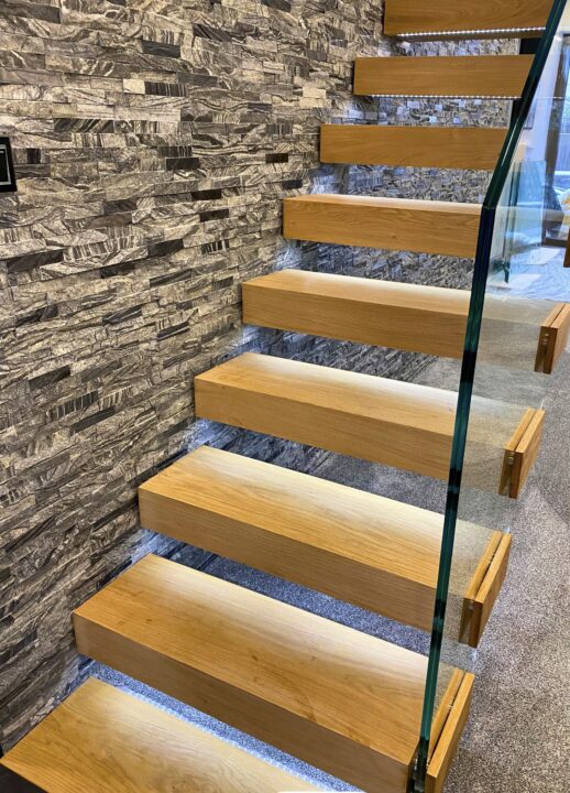 Modern loft room staircase with steel spine, oak treads and glass balustrade, ideal as a stylish loft bedroom staircase in open-plan interiors.