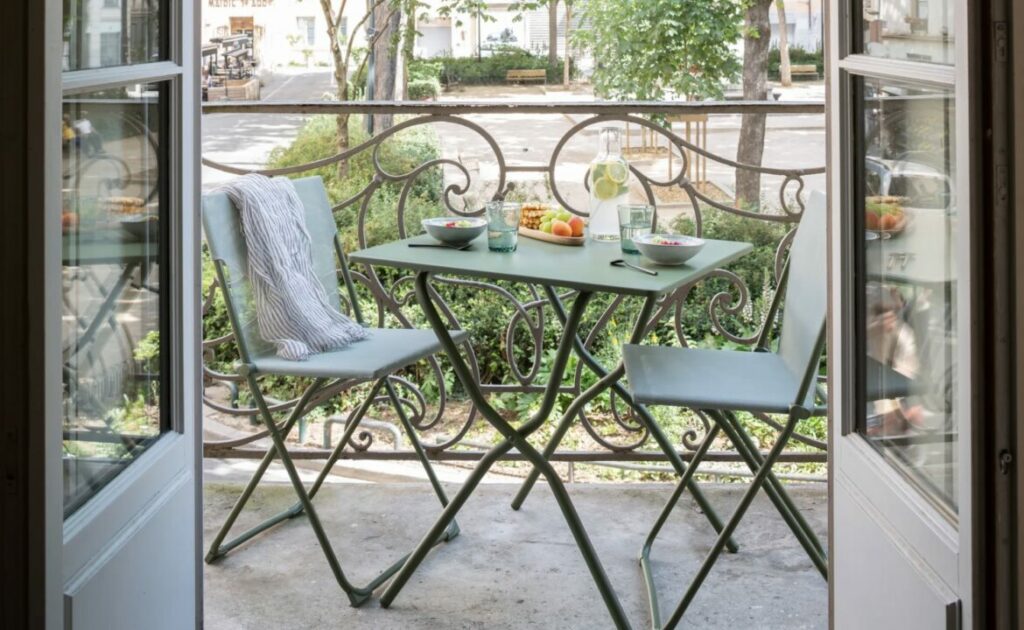 Small balcony with a Lafuma folding bistro table and chairs, set for outdoor dining with drinks and fresh fruit – a stylish and functional small balcony idea.