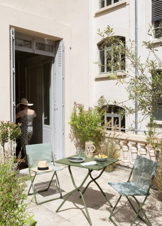 Small balcony with a Lafuma folding bistro table and chairs, surrounded by greenery – a stylish and space-saving small balcony idea.