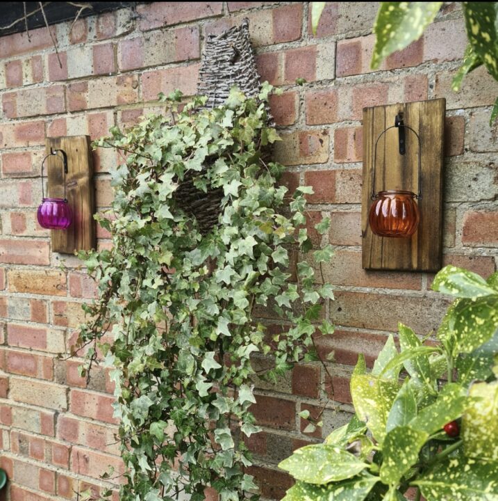 Wall-mounted lanterns with cascading greenery, creating a charming and atmospheric small balcony design.
