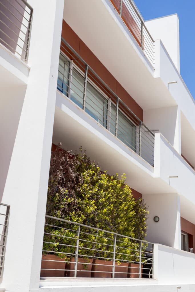 Small balcony privacy idea using tall potted shrubs along a railing to create a natural green screen