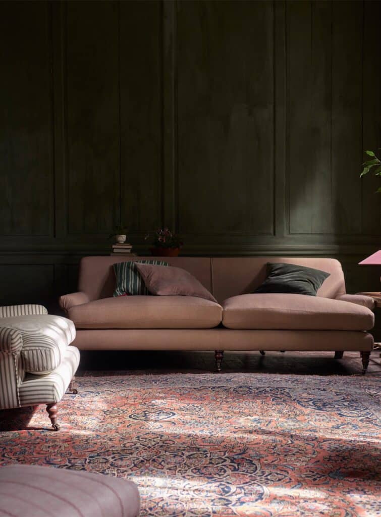 Rowen & Wren's Remy Sofa in Plaster Pink Linen, three-seater, against dark green panelled walls with a striped armchair and antique rug