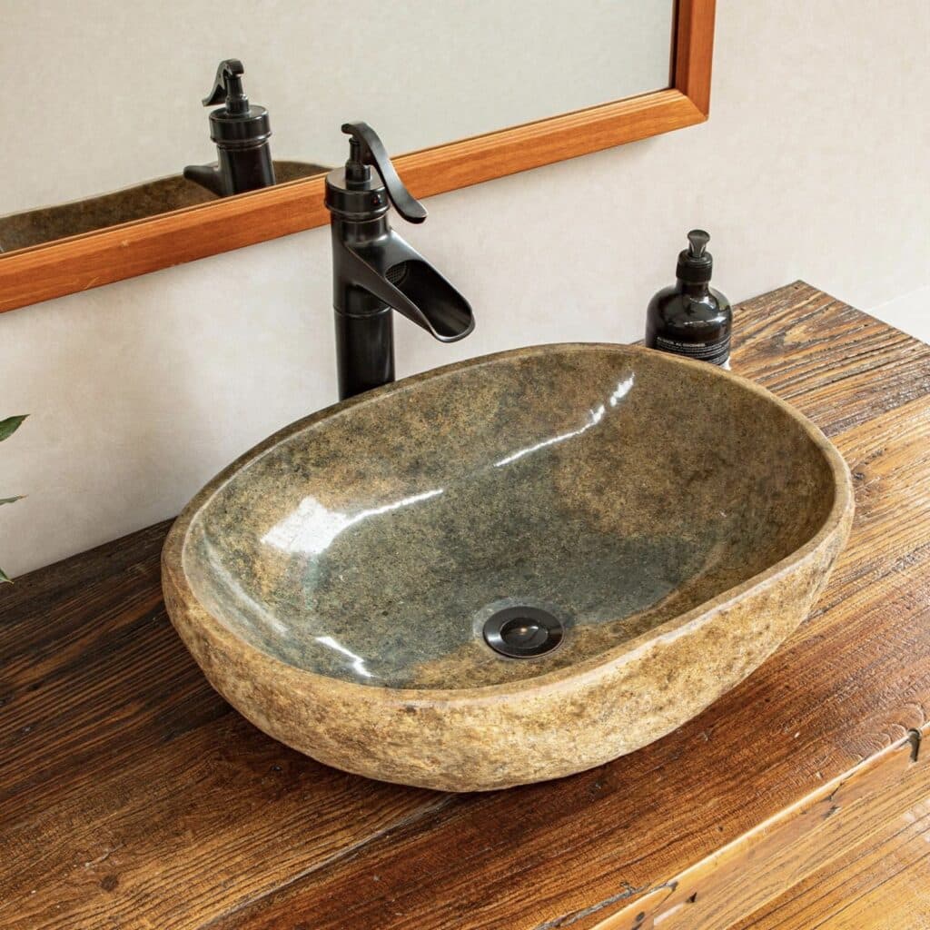 Handmade natural river stone oval vessel basin on reclaimed wood vanity with black tap and oak framed mirror