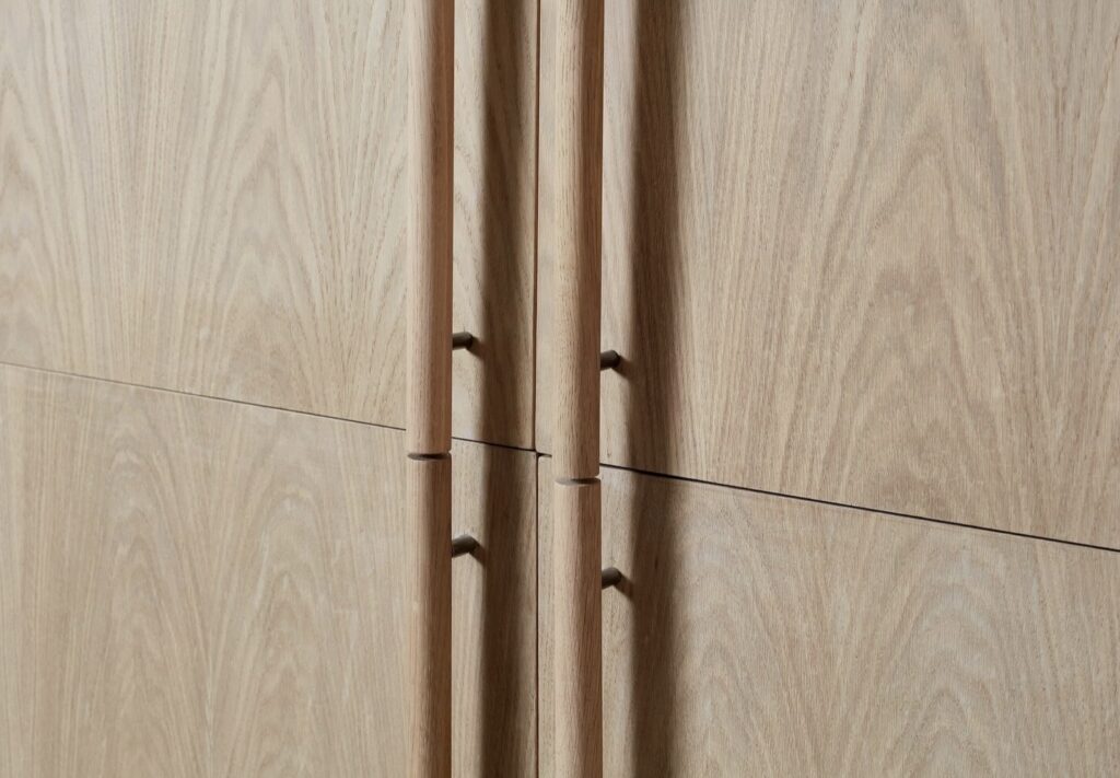 Natural oak bar pull handles on flat panel japandi kitchen cabinet doors showing clean minimal hardware detail
