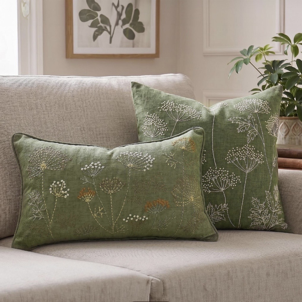 Beige sofa styled with sage green embroidered botanical cushions, creating a calm and nature-inspired living room.