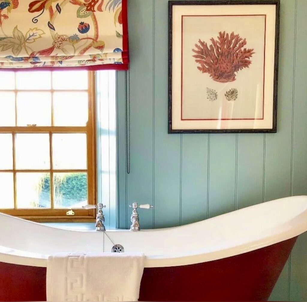 Bathroom with wood panelling in Oval Room Blue and freestanding red bath by Farrow & Ball