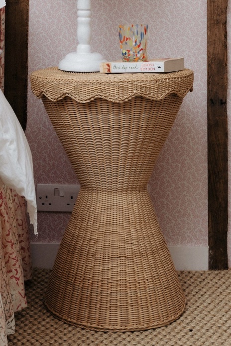Scalloped rattan side table styled with a lamp – ideal for cottage bedroom ideas.
