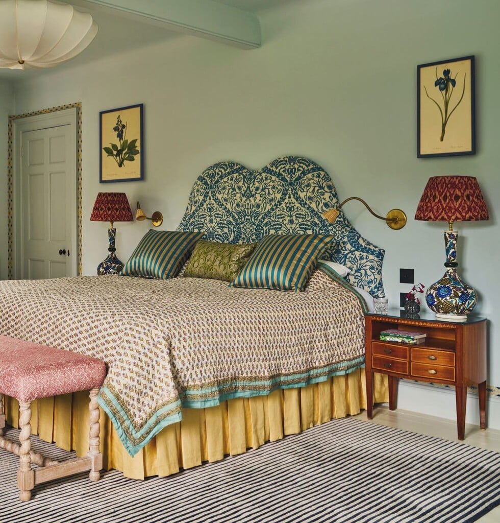 Blue and gold bedroom with patterned headboard, mustard bedskirt and botanical wall art