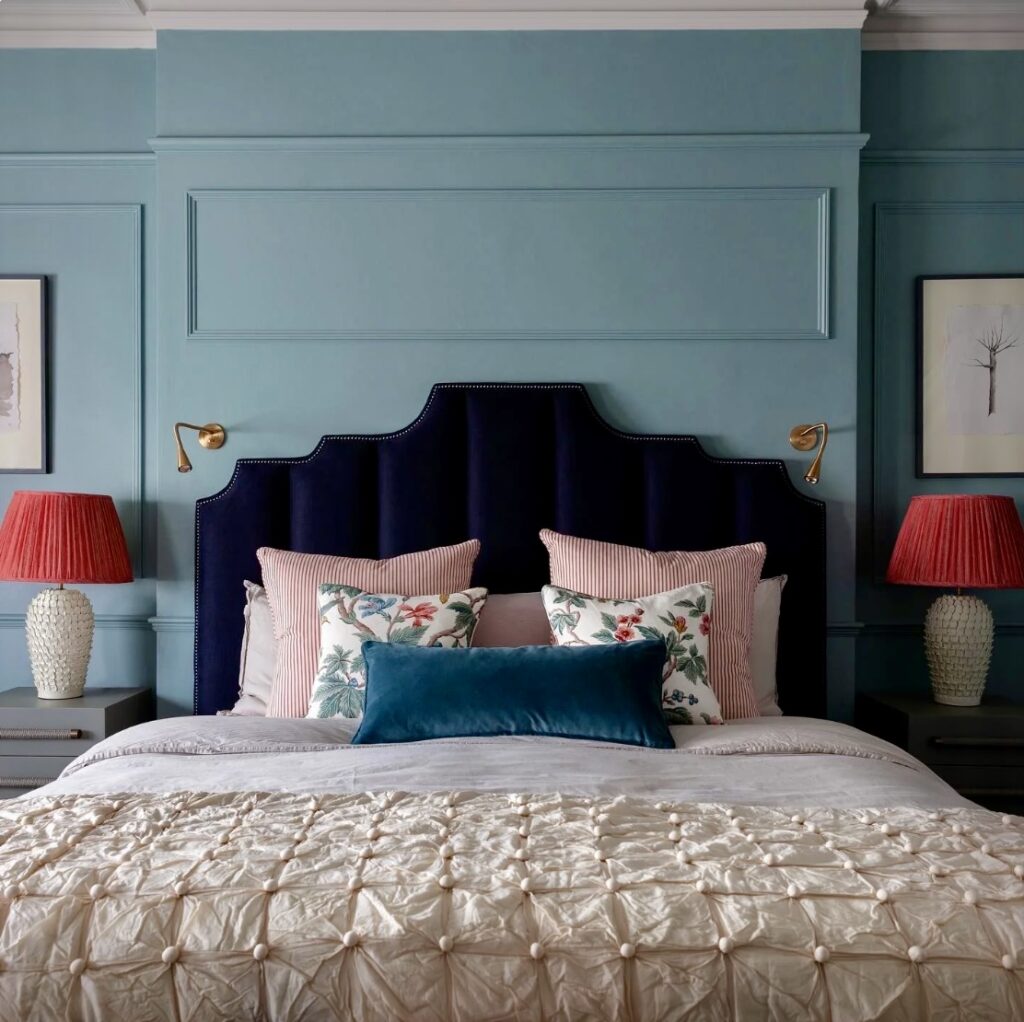 Oval Room Blue panelled bedroom with navy headboard and pink lamps – layered blue bedroom ideas.