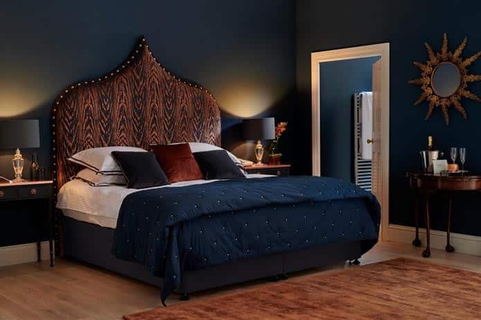 Navy blue bedroom with Farrow & Ball Hague Blue walls and rust-toned ikat headboard