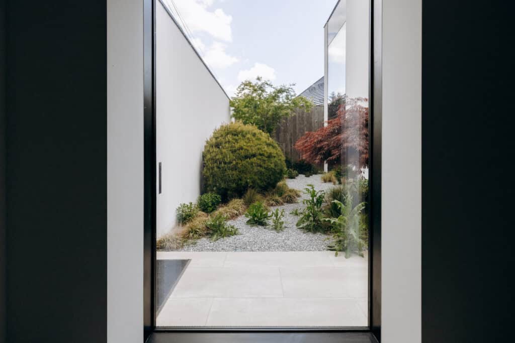 Gravel garden ideas showing a calm courtyard garden viewed through a large window with minimalist planting